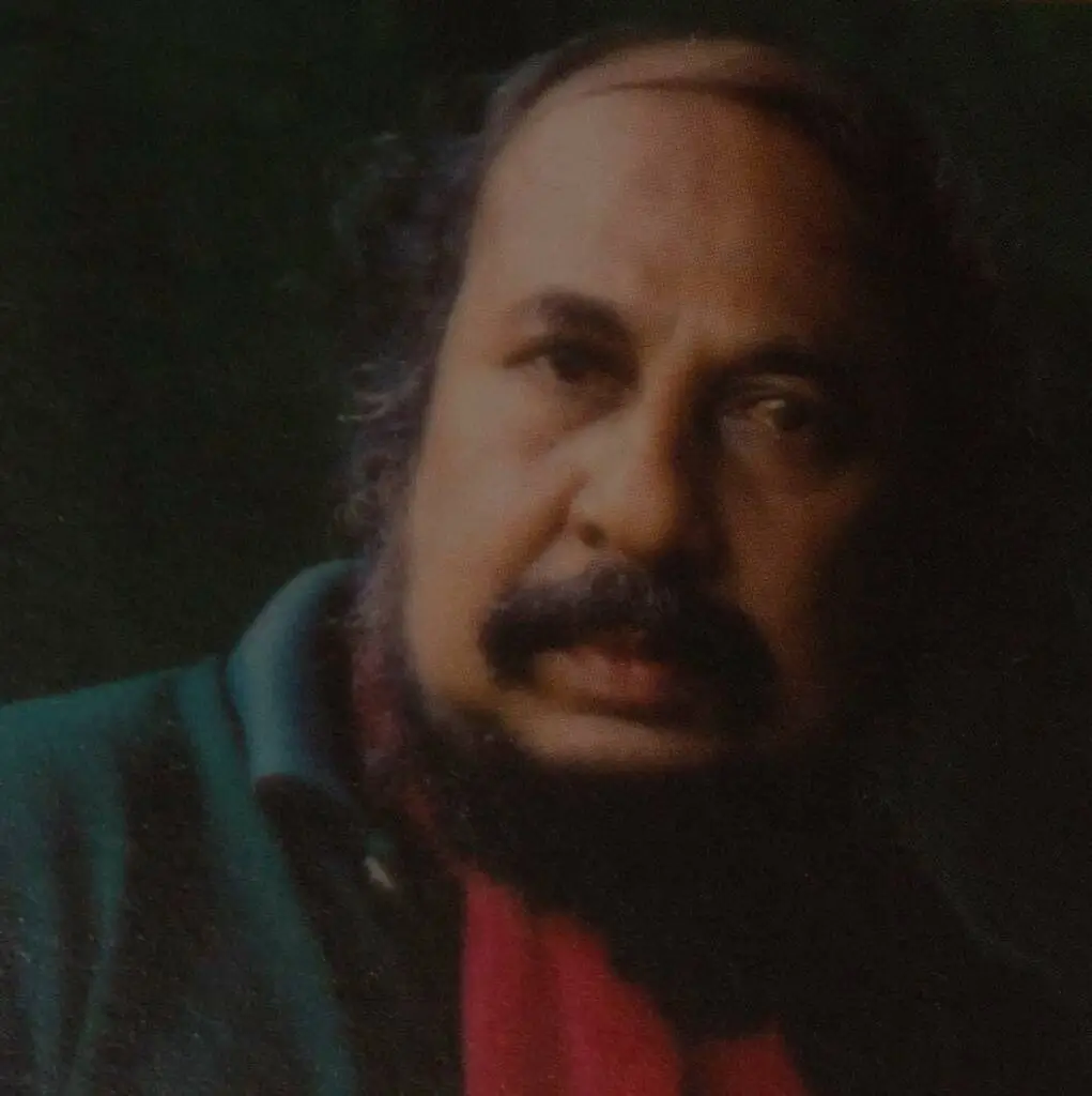 A man with a beard wearing a red scarf, exuding a warm and stylish appearance.