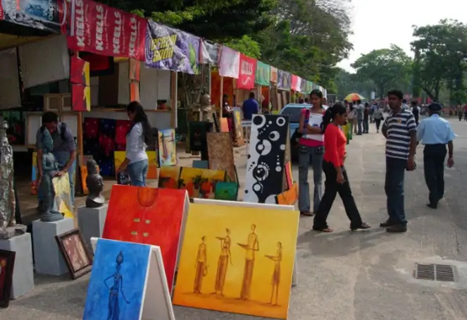 A lively street scene with numerous people strolling and various artworks exhibited, creating an engaging environment.