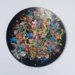 A black plate displaying an array of vibrant, colorful paint splatters artistically arranged on its surface.