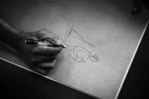 A person sketching a figure on a sheet of paper, focused on their artistic creation.