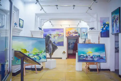 An art gallery featuring various paintings elegantly displayed on the walls, showcasing diverse artistic styles and colors.
