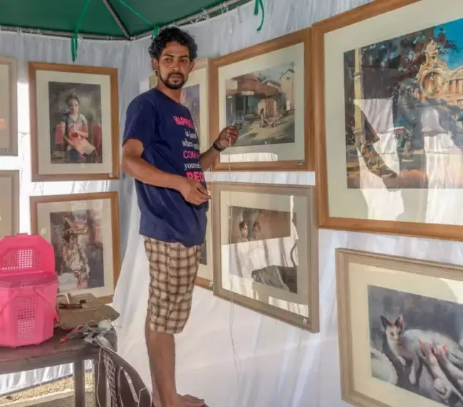a man hanging art works on the kalapola event store