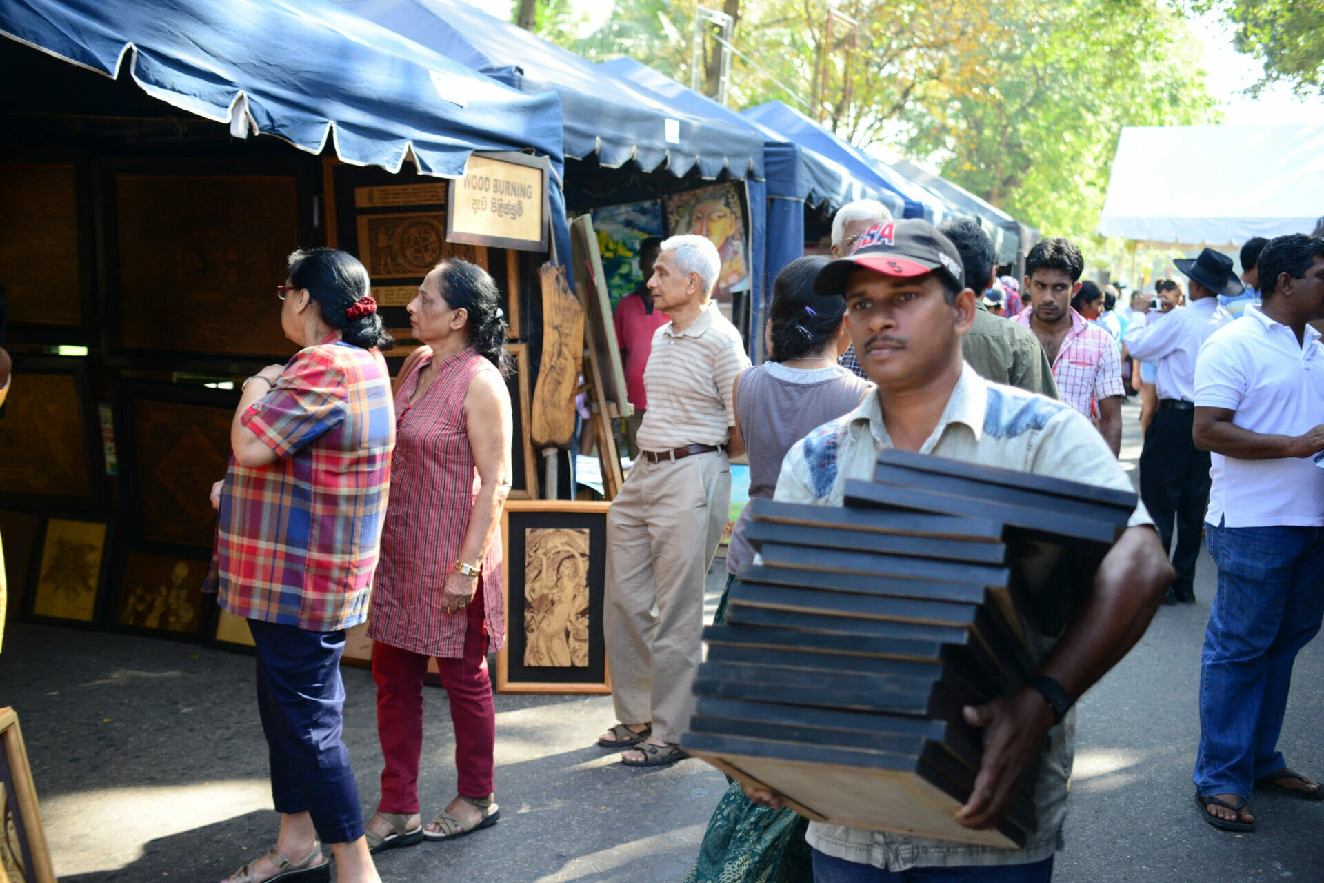A man is seen carrying a large wooden boxes, showcasing strength and determination in his posture.