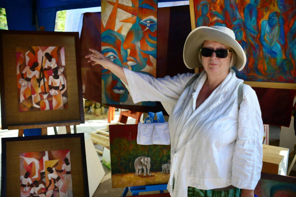 A woman dressed in a white shirt, standing confidently with a neutral background.