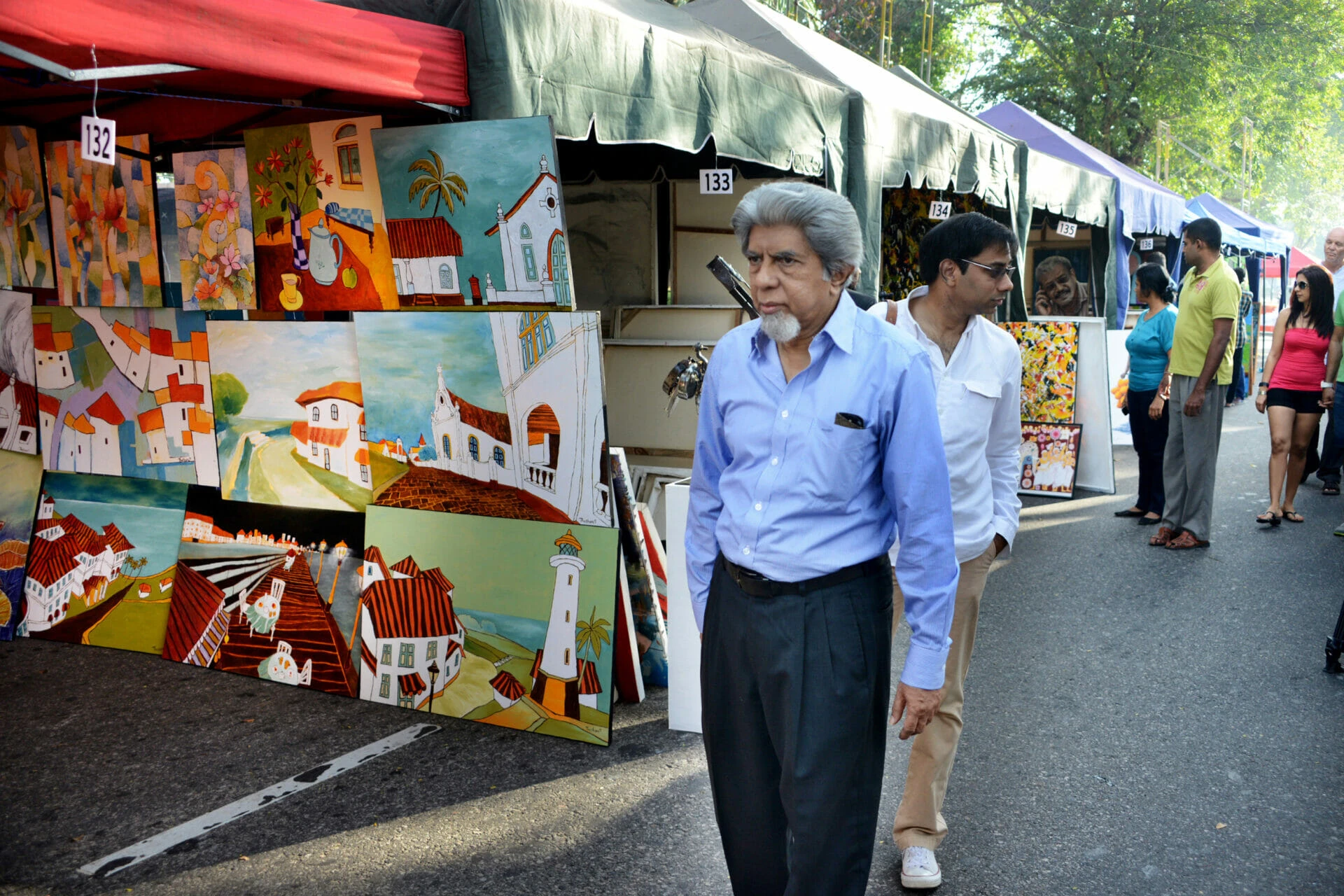 A man strolling down a bustling street, with shops and pedestrians in the background.