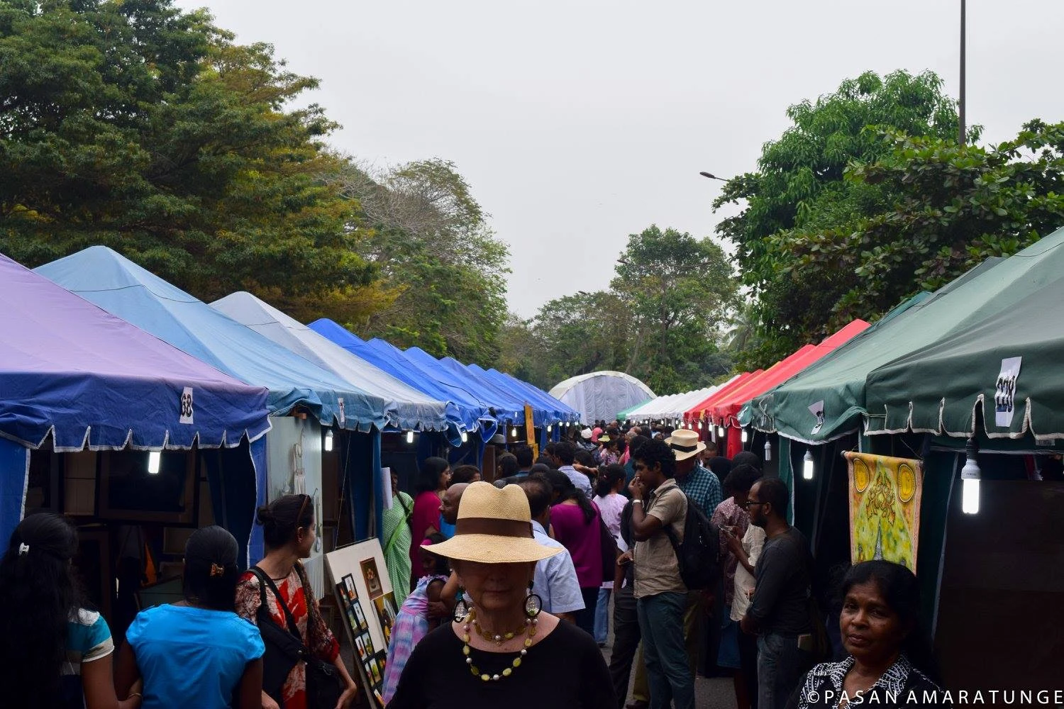 A vibrant market scene with a crowd of people walking among colorful tents, reminiscent of children's drawings.