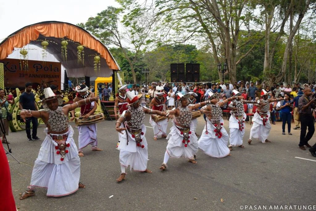 A group of people in traditional attire dances joyfully, surrounded by colorful drawings made by children.