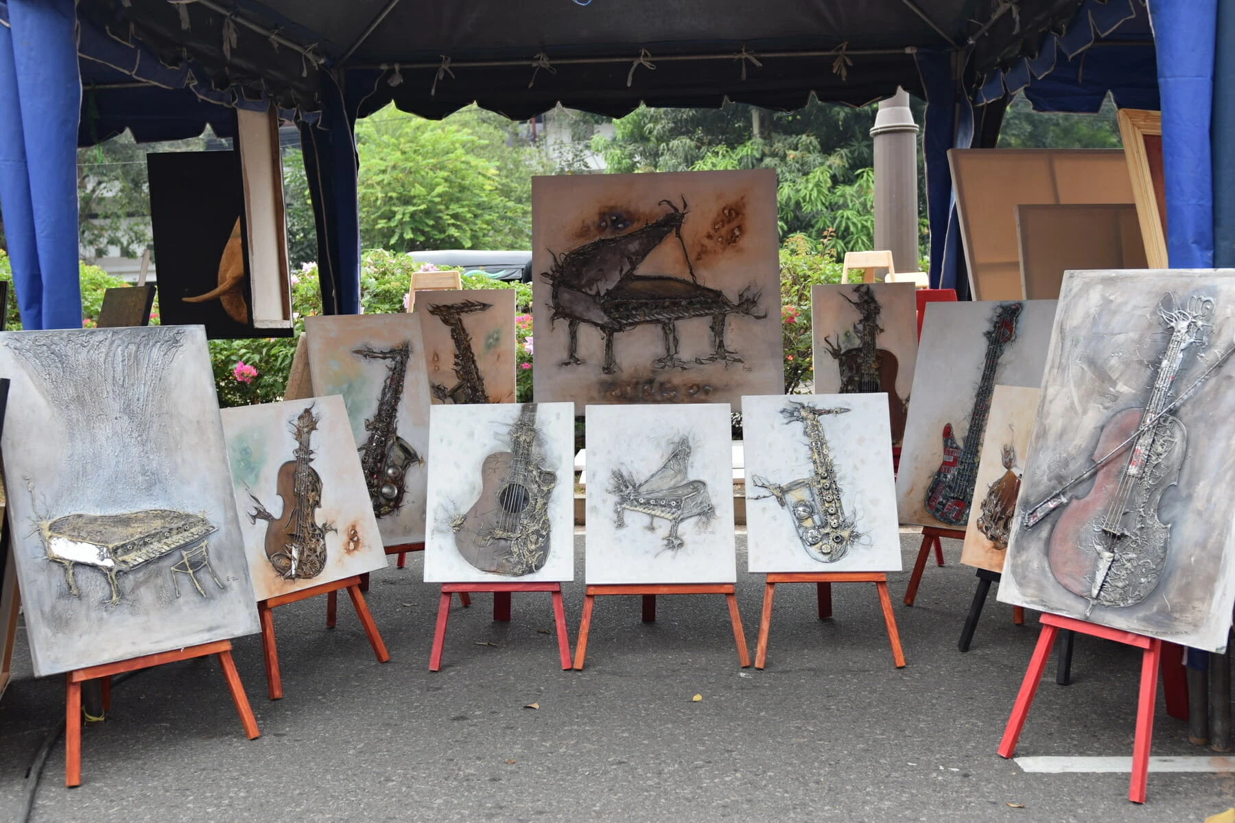 A tent displaying easels with vibrant paintings of various musical instruments.