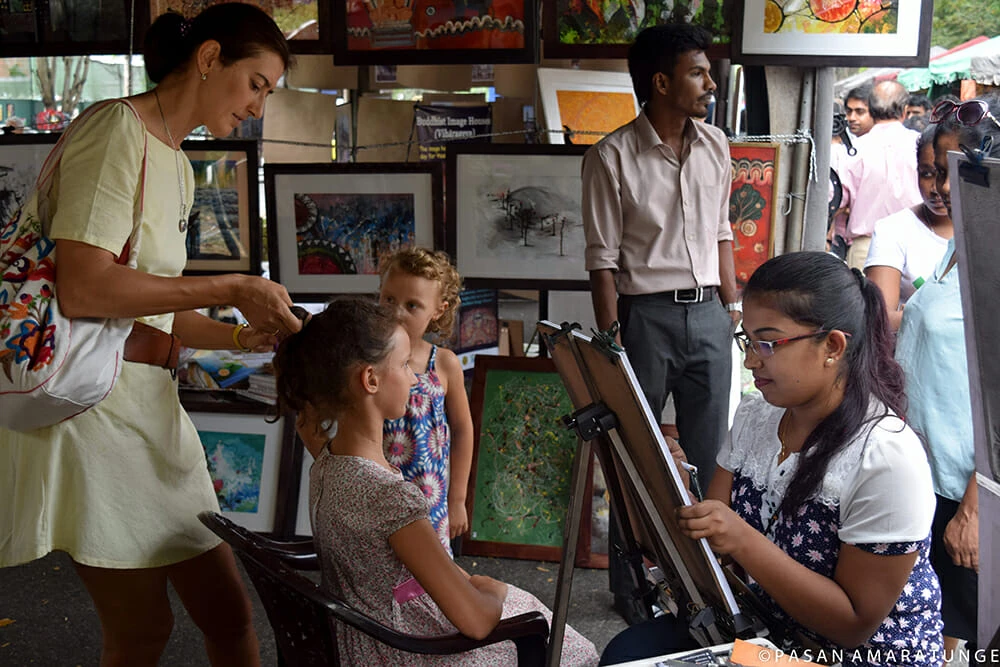 A woman is engaged in painting a child's face, showcasing vibrant colors and a playful atmosphere.
