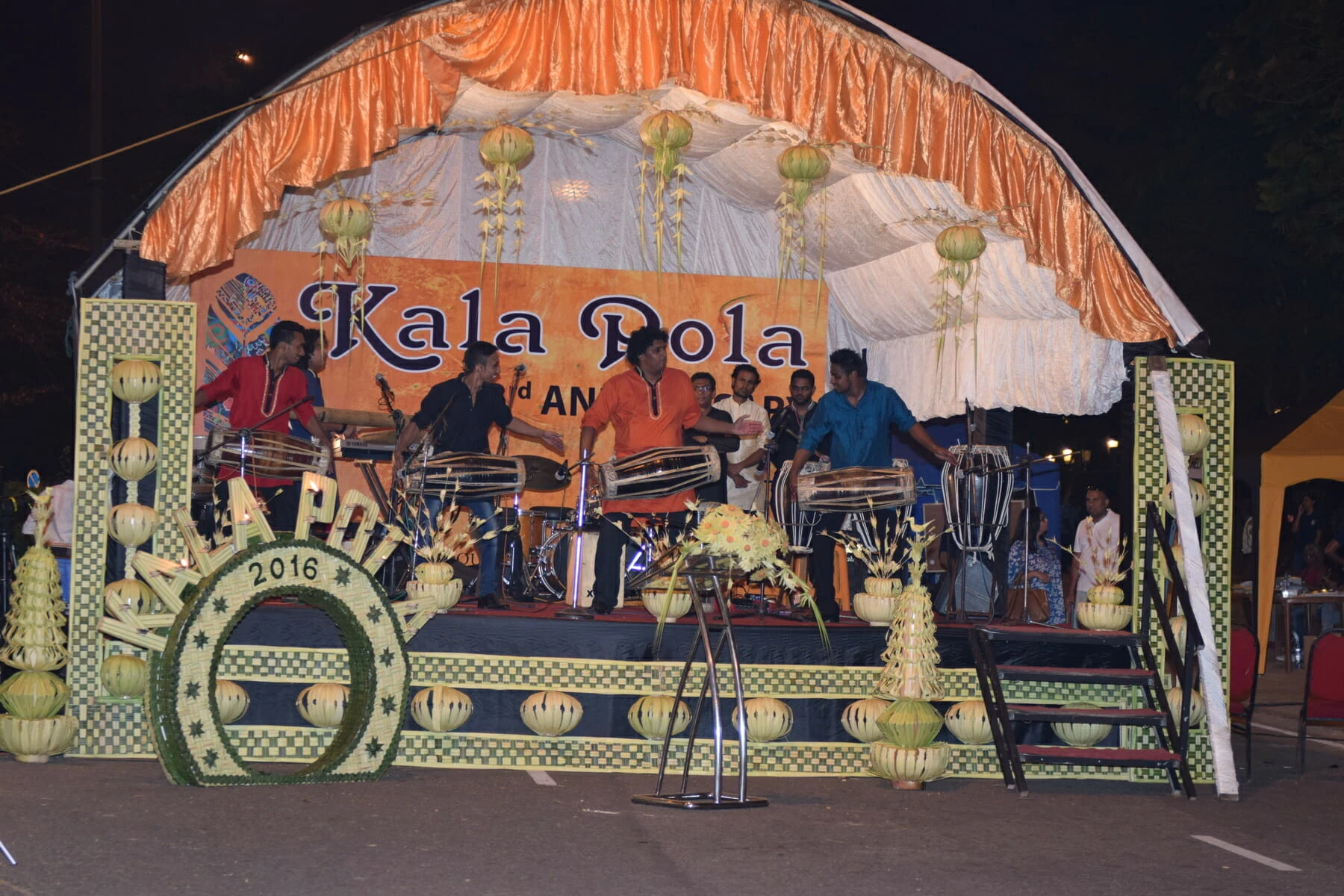 A lively stage featuring a band performing energetically, with instruments and colorful lights enhancing the atmosphere.