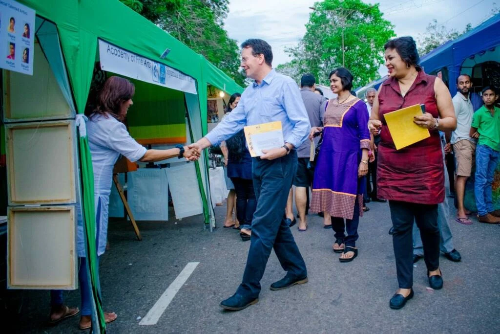 A man engaging in a handshake with individuals under a tent, symbolizing connection and collaboration.