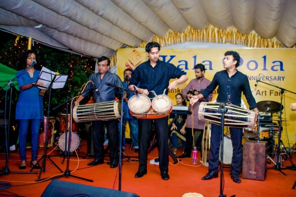 A group of men enthusiastically playing drums and various instruments at a lively festival celebration.
