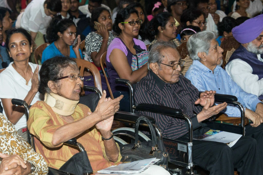 A diverse group of individuals seated in chairs, engaged in conversation and sharing ideas in a collaborative setting.
