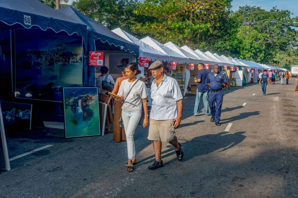 A man is engaged in painting a car, with multiple paintings hanging in the background.