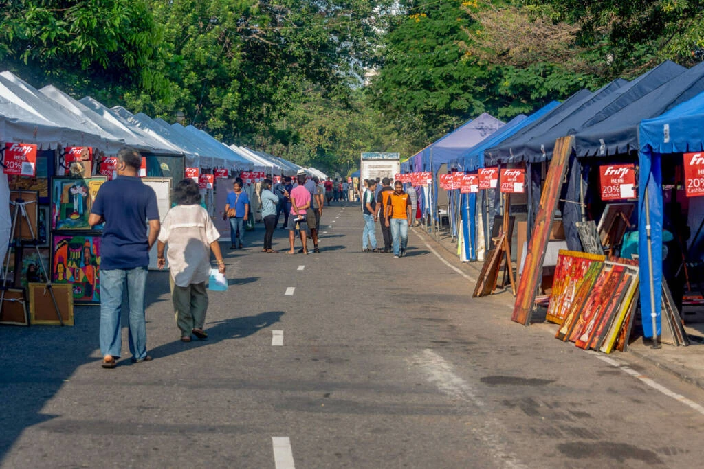 A man and woman stroll down a street lined with tents, enjoying a vibrant outdoor atmosphere.