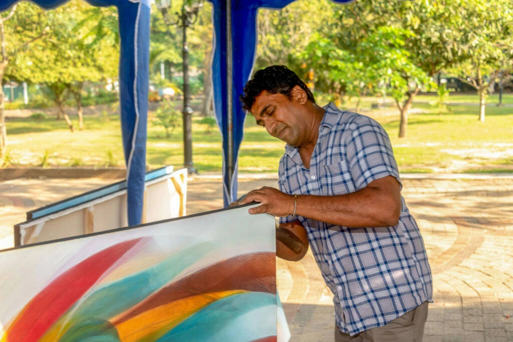 A group of individuals engaged in creating art at a vibrant market stall, showcasing their creativity and craftsmanship.