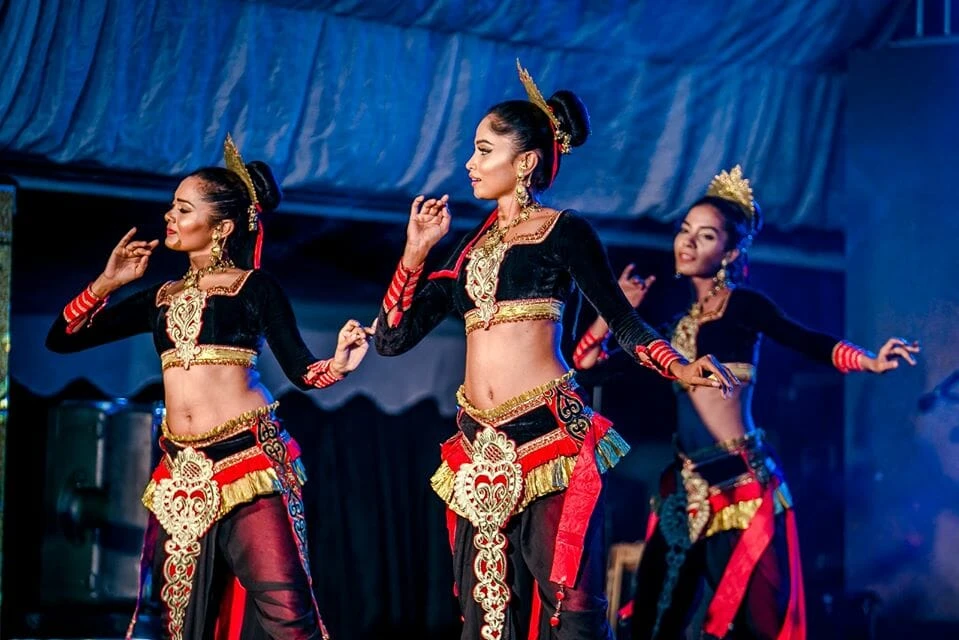 Two women explore various artworks at an outdoor market, appreciating the artistic expressions in a bustling environment.