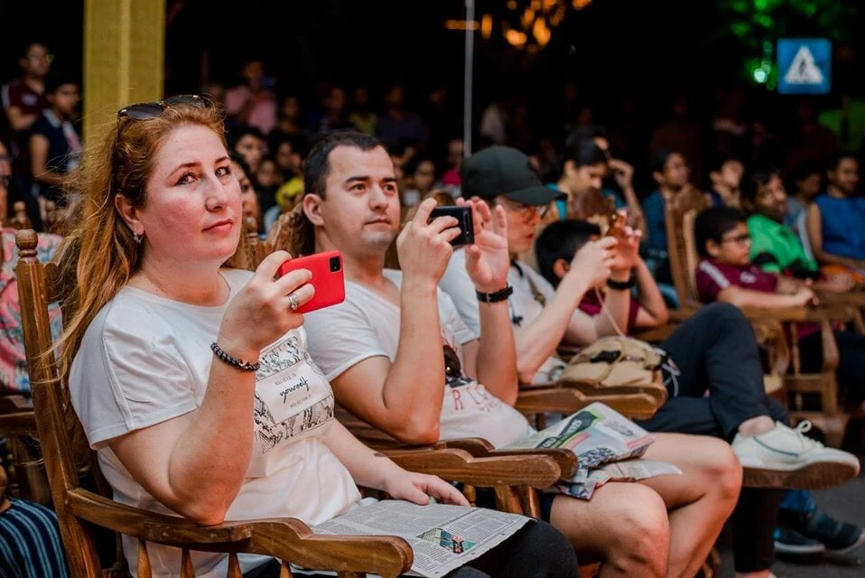 A man and woman stand at a podium adorned with flowers, engaged in a formal discussion or presentation.