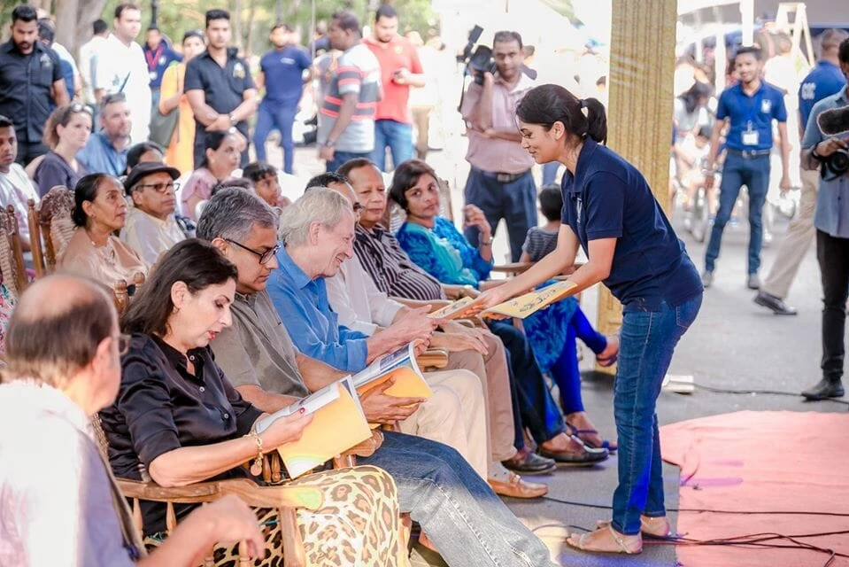 A couple walks together in a lively market, surrounded by a diverse crowd and colorful vendor displays.