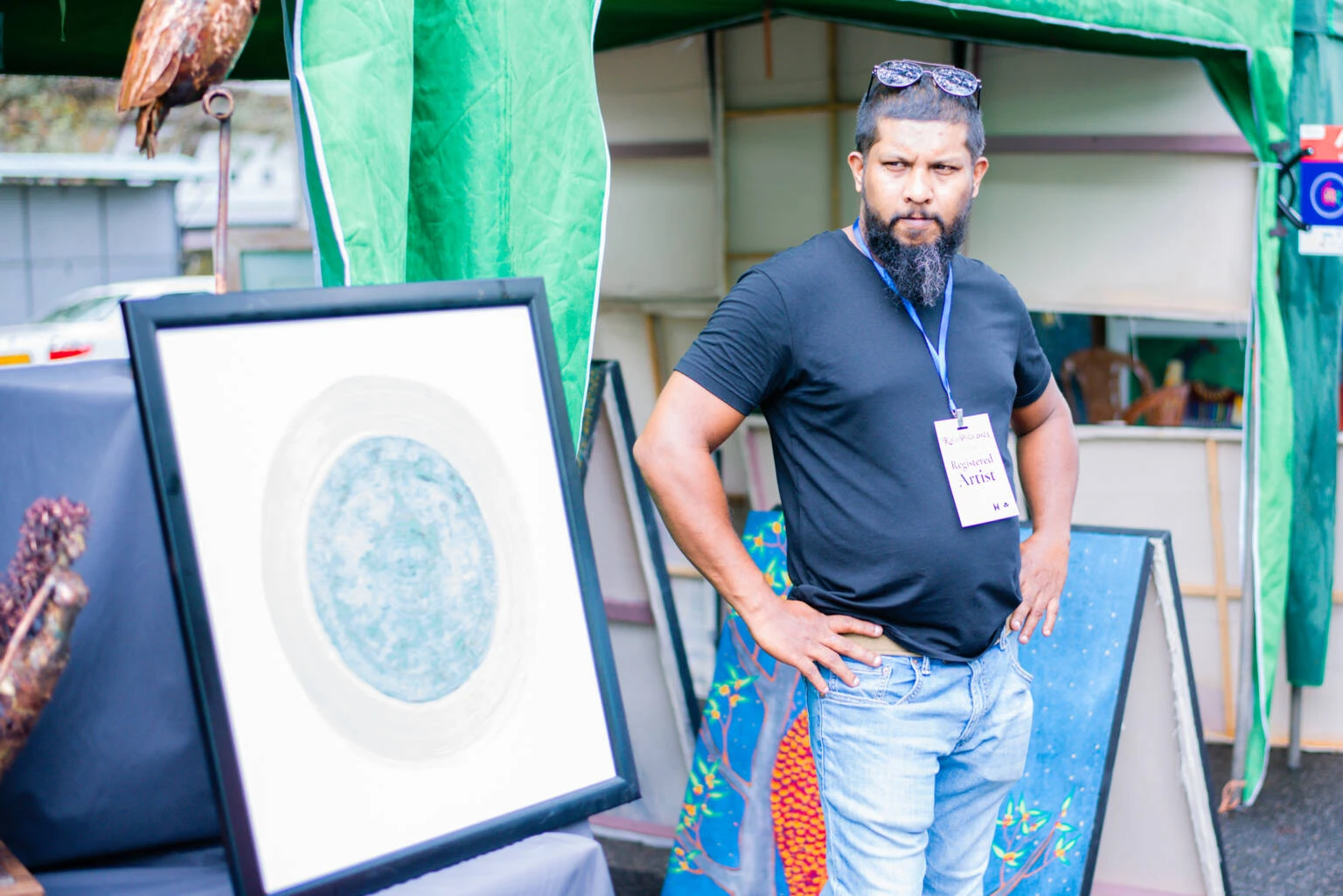 A man dressed in a dark blue shirt stands confidently, showcasing a casual yet stylish appearance.