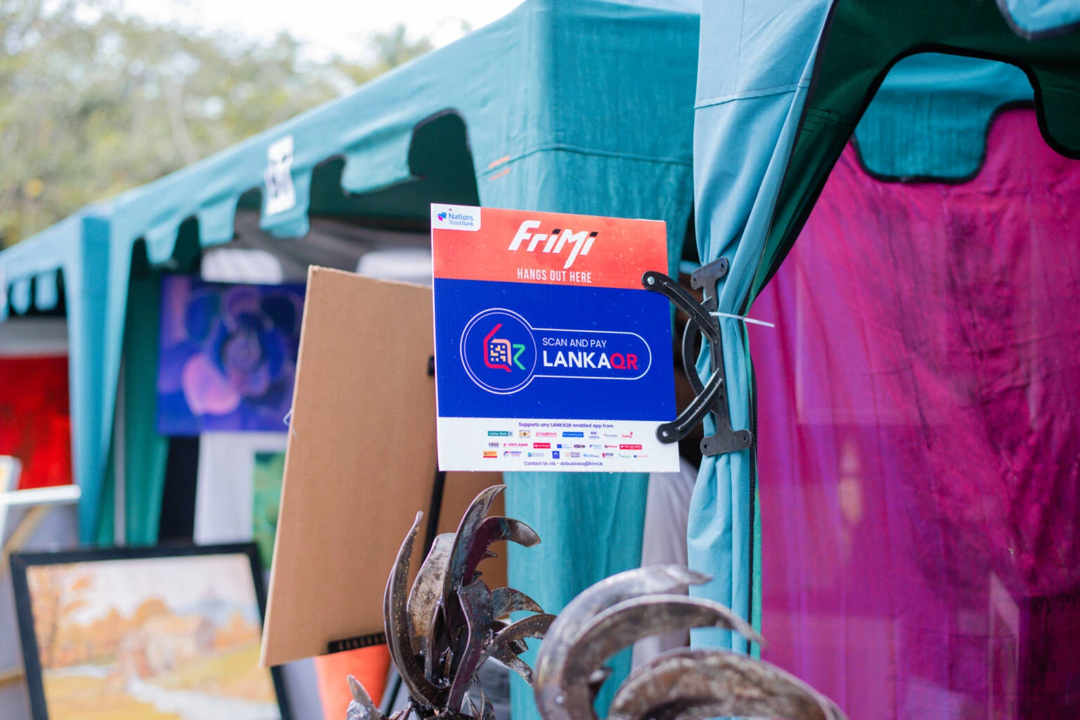 A board sign that says "frimi" accompanied by a QR code from Nation Trust Bank.
