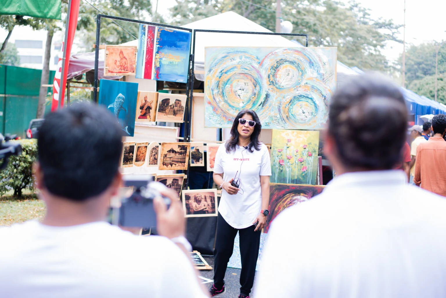 A woman captures images of a painting, appearing to present the artwork to an unseen audience.