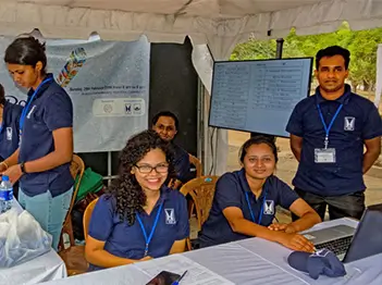 Several people engaged in discussion around a table, focused on their laptops as they work together.