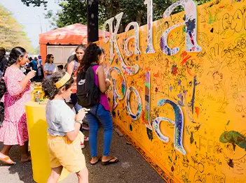 Individuals congregate near a wall featuring colorful graphic, representing urban expression and collective presence.