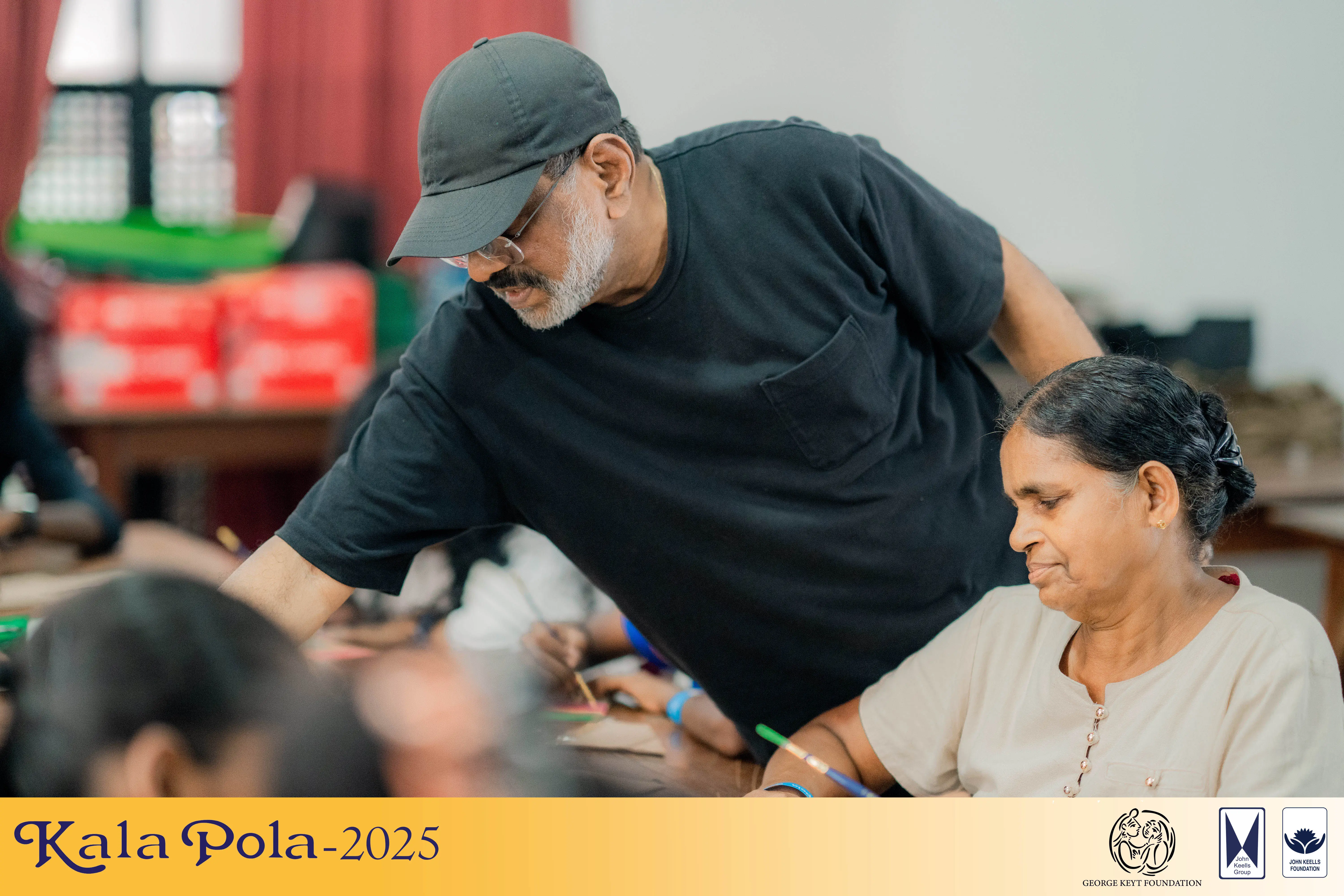 Two women collaboratively painting on paper at a table, showcasing creativity and teamwork in their artistic endeavor.